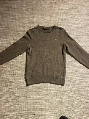 Grå  tröja från Morris - Grå rundhalsad tröja från Morris med logga broderad på bröstet. Tröjan har långa ärmar och är tillverkad i ett tunt, mjukt material som passar perfekt till lager-på-lager. Enkel och stilren design. Det är en S tröja men den är som en XS-XXS 