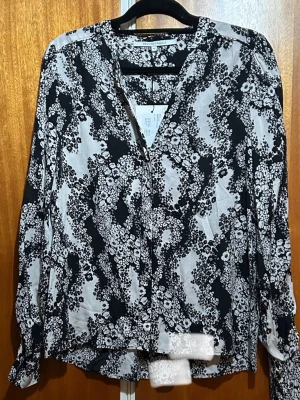 Svartvit blommig blus Second Female - Blus från Second Female i svartvitt med blommigt mönster och v-ringning. Lätt och luftig modell med långärmade ärmar. Perfekt för dig som gillar stilrena och trendiga plagg med en twist.