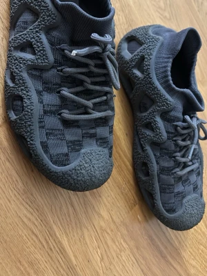 Gråa stickade sneakers med unik sula - Säljer ett par gråa sneakers med stickad ovandel och ett rutigt mönster. Skorna har en chunky, vågig sula med textur och snörning framtill. 