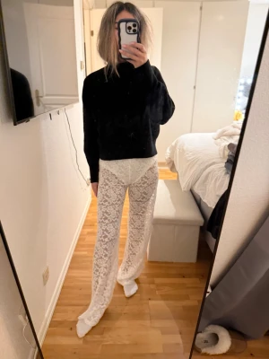 Vita spetsleggings med vida ben - Säljer ett par vita leggings i spets med transparent material och vida ben. De har hög midja och ett elegant mönster i spets som ger en unik look. Perfekt för dig som vill sticka ut och skapa en trendig outfit. Är ca 163. Har inbyggda shorts.