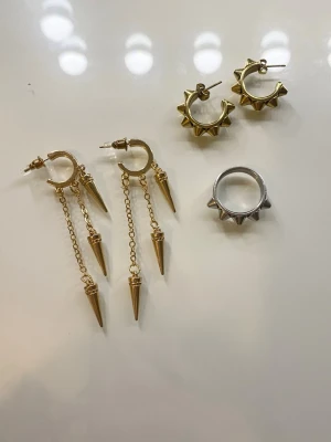 säljer lågt i bara några dagar  - säljer 2 par örhängen och 2 par ringar (går bra att köpa dem separat om man vill det) De guldiga hängande örhängena med nitar är från ur och Penn och har aldrig används och kostar 20. De guldiga taggiga örhängena är från Edblad och har använd ett få tal gånger och kostar 200. Och ringen är från Edblad i storlek 16 och kostar 150. Om man vill köpa alla 3 kostar det 250, eftersom att den två från Edblad kostar 349 och 399 💞. 