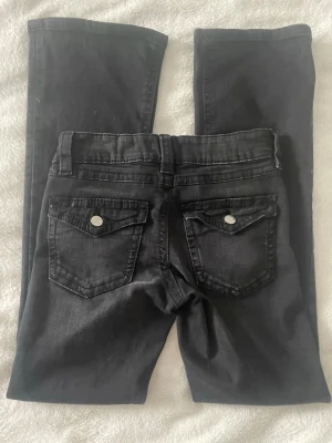 Svarta jeans från Gina Tricot - Svarta jeans från Gina Tricot med lite utsvängda ben  och snygga bakfickor. Storlek 152. Klassisk femficksmodell. Nästan aldrig använda. Jag är 152cm lång