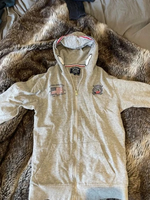 Polo club zip hoodie - Grå polo club hoodie med USA 🇺🇸 detaljer.                    Hoddien passar 12-13 y.  Slå bare en pling 🛎️ kring några funderingar.