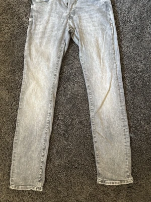 Ljusgrå slim fit jeans från Jack and jones - Säljer ett par ljusgrå slim fit jeans från Jack and Jones. Modellen heter Slim Glenn och storleken är 28/30. Minimal defekt vid bakfickan ses på tredje bilden.
