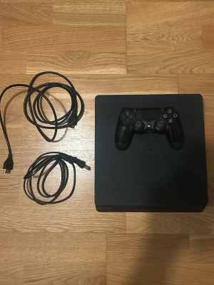 PlayStation 4 Slim med handkontroll - Säljer en svart PlayStation 4 Slim från Sony med tillhörande svart DualShock 4-handkontroll. Ps4 fungerar utmärkt och har inga problem. Den sälj pogrjnd av att den inte används längre. Det tillkommer kontroll, alla kablar och en laddare till kontrollen. 