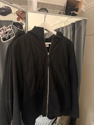 Svart hoodiejacka från C.P. Company - Svart C.P. Company cardigan i svart i storlek M med dem ikoniska glasögonen på luvan, ena glaset saknas, är lite lätt solblekt på sina ställen men väldigt fet och fin fortfarande, nypris 4699kr mitt pris 900kr (pga solblekt/ normalt lätt slitage)