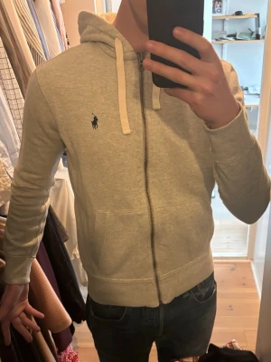 Ljusgrå Ralph Lauren zip hoodie - Ljusgrå Polo Ralph Lauren zip hoodie i mycket bra skick. Har en riktigt snyggpassform och är i storlek S