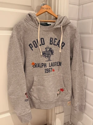 Grå hoodie Polo Bear Ralph Lauren - Grå hoodie från Ralph Lauren med Polo Bear-tryck. Tröjan är limited edition och finns inte att få tag på idag. Mycket gott skick, nypris 3000. Krymt i tvätt tyvärr så trotts att den är märkt som M passar den S. Pris kan diskuteras, byter ej! 