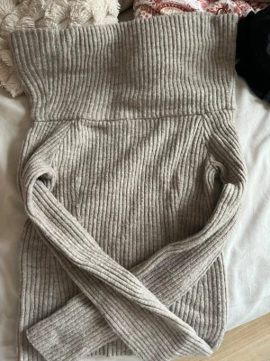 Beige ribbstickad off-shoulder  - Säljer en beige ribbstickad off-shoulder från H&M. Tröjan har lång ärm, är gjord i mjukt stickat material. Perfekt för lager på lager och en clean look till hösten och vintern.