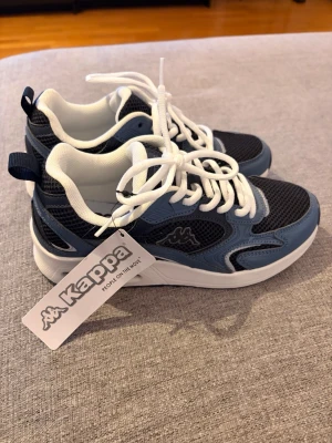 Blå och svarta sneakers från Kappa - Snygga sneakers från Kappa i blått och svart med vita detaljer. Helt nya, aldrig använt. 