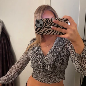 Leopardmönstrad croppad volangblus  - Croppad blus med leopardmönster och volangdetalj vid ringningen. Långa ärmar och smockad midja🤍🤍
