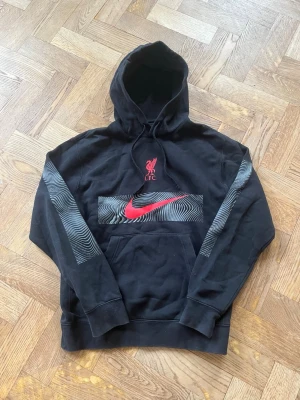 Liverpool hoodie - Svart hoodie från Nike med tryck från Liverpool FC. Skön och sportig modell med ficka framtill och huva. Tröjan är använd men i bra skick. Nypris ca 749🙌