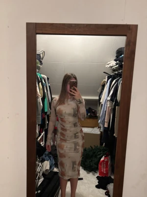 Mönstrad långärmad klänning - Trendig långärmad klänning med abstrakt mönster i beige, brun och grå toner. Klänningen har en kroppsnära passform och går ner till knäna. Perfekt för dig som gillar unika plagg med snygg siluett.