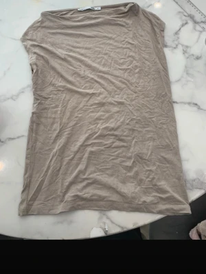 Beige ärmlös topp i bomull - En enkel och stilren beige topp i mjuk bomull. Modellen är ärmlös med rund halsringning och rak passform, perfekt att matcha med jeans eller kjol. Snygg basic som funkar till många olika looks.