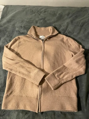 Beige ziptröja med hög krage - Mysig beige tröja med dragkedja framtill och hög krage. Tröjan har långa ärmar och ribbade muddar vid ärmslut och nederkant. Perfekt för lager på lager och enkel att matcha med olika outfits. Storlek är L men har krympt väldigt mycket.