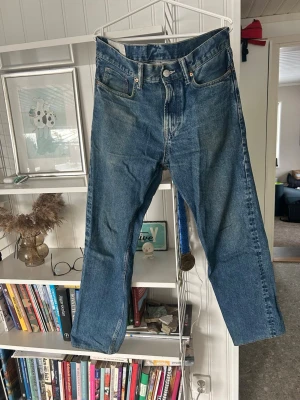 Blå raka jeans med hög midja - Säljer ett par klassiska blå jeans med rak passform. Jeansen har fem fickor, dragkedjegylf och är tillverkade i kraftig denim. Perfekta för en avslappnad och tidlös stil. Det är straightfitmodell.