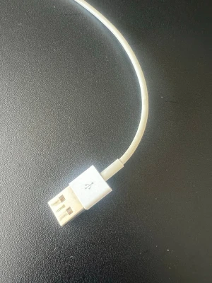 Vit USB till Lightning-kabel - En vit USB till Lightning-kabel som passar till iPhone och andra Apple-enheter. Kabeln är gjord av plast och har en klassisk, slimmad design med USB-A i ena änden och Lightning-kontakt i andra. Perfekt för laddning och synkronisering av din mobil.