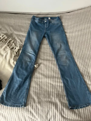 Blåa bootcut jeans - Säljer ett par ljusblå(mörkljusblå) bootcut jeans med klassisk femficksmodell och normal midja. Jeansen har en snygg tvätt med lätt slitning framtill och vida ben som ger en retrovibe. Perfekta till sneakers eller boots för en cool look.