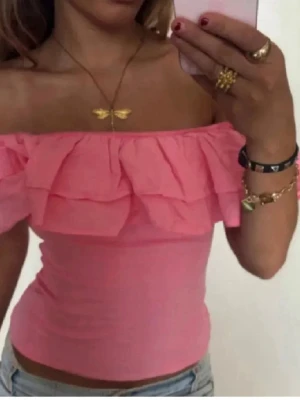 Rosa offshoulder topp med volang - Söt rosa offshoulder topp med dubbla volangdetaljer runt axlarna. Toppen är tight och croppad. Lappen är inte kvar men skulle säga att storleken är XS/S