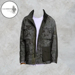 Camouflage Field Jacket Tommy Hilfiger - Tommy Hilfiger Camouflage Field Jacket en modern tolkning av den klassiska militärjackan i stilrent kamouflagemönster. Luvan med dragsko kan smidigt döljas i kragen och jackan stängs med både dragkedja och tryckknappar. Invändig justering i midjan för en mer markerad och anpassad passform. Utgången modell som är svår att få tag på idag. Skick 8/10 sparsamt använd och utan defekter. Storlek L. Hör av dig för mått! ~ Nypris var 3 400–4 300 kr | Mitt pris 1 199 kr (öppen för förslag). Alla följar