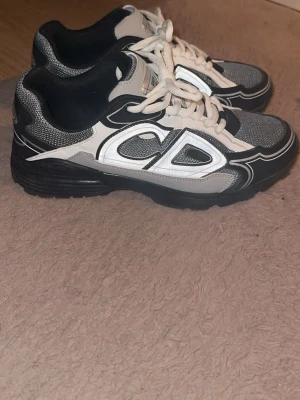 Dior b30 - Snygga Dior sneakers i svart, vitt och grått med reflekterande detaljer och tydligt CD-märke på sidan. Ovandelen är i mesh och läder, med vita snören och svart sula. Perfekta för dig som vill sticka ut med exklusiva och trendiga skor. Använt 1 gång, pris kan diskuteras