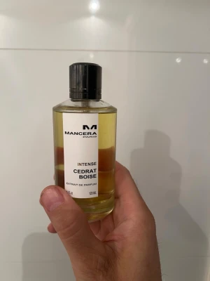 Mancera Cedrat Boise Intense parfym - Mancera Cedrat Boise Intense är en exklusiv parfym i en genomskinlig glasflaska med svart lock. Flaskan rymmer 120 ml och har en stilren vit etikett med svart text. Doften är känd för sina fräscha och träiga noter.
