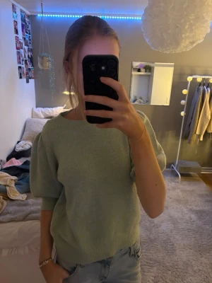 Ljusgrön stickad tröja med puffärm - Säljer en ljusgrön stickad tröja med puffade ärmar och ribbade detaljer vid hals, ärmslut och nederkant. Tröjan har en rund halsringning och är tillverkad i ett mjukt material som passar perfekt för lager-på-lager. Märket är Vero Moda.