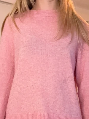 Ljusrosa stickad tröja (tar emot bud) - Mysig ljusrosa stickad tröja med rund halsringning och ribbade muddar vid ärmslut och nederkant. Tröjan har en avslappnad passform och är perfekt för lager-på-lager. Passar dig som gillar en enkel men söt stil. Tyvärr så har tröjan en liten fläck på magen, men fortfarande användbar