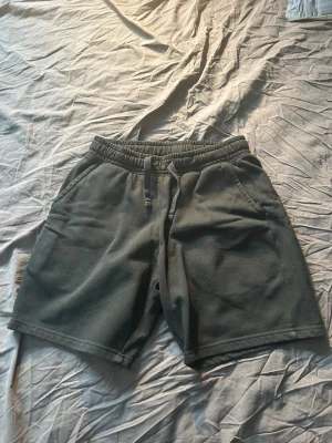 Svarta mjukisshorts med snörning - Svarta shorts i mjukt bomullsmaterial med elastisk midja och snörning framtill. Två fickor fram och en bakficka. Perfekta för chill dagar eller träning. Klassisk och enkel design som är lätt att matcha.
