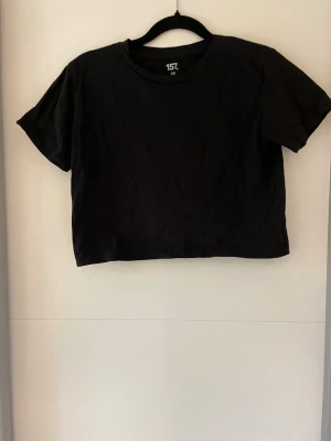 Kortare svart t-shirt - En enkel svart croppad t-shirt från 157 med rund halsringning och korta ärmar. 