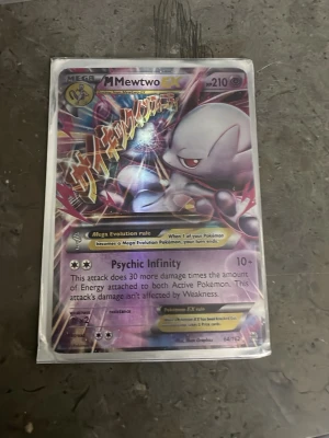 Pokémonkort Mega Mewtwo EX - Säljer ett Pokémonkort Mega Mewtwo EX med holografisk yta. Kortet har lila och silvriga färger med japansk text och motiv av Mewtwo. Kortet är inplastat och har Psychic Infinity-attacken. Perfekt för samlare eller Pokémonfans.