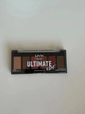 NYX Ultimate Edit ögonskuggspalett - NYX Ultimate Edit ögonskuggspalett med sex nyanser i varma toner som beige, brunt och rött. Kompakt och smidig för att ta med sig, perfekt för att skapa olika ögonlooks. Paletten har ett genomskinligt lock och rektangulär form.