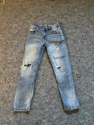 Ljusblå jeans från LAB Industries - Snygga ljusblå jeans från LAB Industries med klassisk femficksdesign och raka ben. Jeansen har slitna detaljer och en läderpatch med logga bak i midjan. Perfekta för en avslappnad och trendig look.