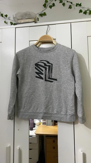 Grå sweatshirt med svart grafiskt tryck - Snygg grå sweatshirt från Esprit med ett svart grafiskt tryck på bröstet. Tröjan har rund halsringning, ribbade muddar vid ärmslut och nederkant. Perfekt för en avslappnad och trendig stil.