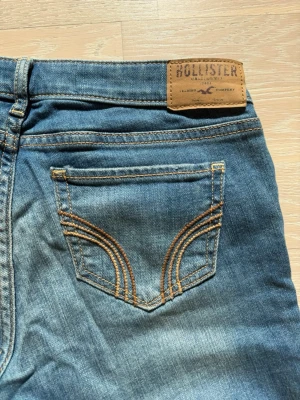 Blå Hollister jeans  - Snygga blåa low waist jeans från Hollister som är helt oanvända. Bakfickan har dekorativa sömmar och tillverkade i mjukt denimtyg. Skriv vid minsta fundering!🌸