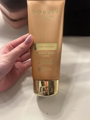 Bobbys Tan Lotion Brun utan sol - Brun utan sol-lotion från Bobbys Hair Care i en snygg guldig tub med gulddetaljer. Ger gradvis solbrun färg och återfuktar huden. Tillverkad i Sverige och passar för kroppsvård. Produkt till sträcket jag ritat på baksidan, Luktar persika🥰