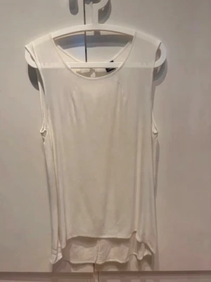 Gina Tricot Topp, stl 40 - Ärmlös topp från Gina Tricot med rund halsringning och en liten öppning baktill. Toppen har en något längre baksida.  Djur- och rökfritt hem.