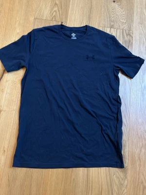 Svart t-shirt från Under Armour - Snygg svart t-shirt från Under Armour med diskret logga på bröstet. Klassisk passform med korta ärmar och rund hals. Perfekt för en sportig och stilren look.