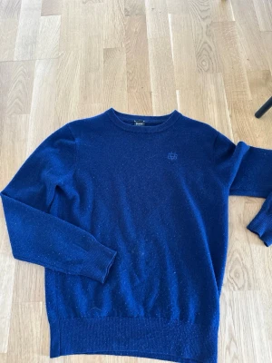 Mörkblå tröja från Bvaldi - Mörkblå stickad tröja från Bvaldi med rund halsringning och diskret logga på bröstet. Tröjan har långa ärmar och ribbade muddar vid ärmslut och nederkant. Perfekt för lager-på-lager och enkel att matcha med jeans eller kjol. Pris kan diskuteras 