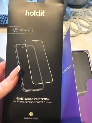 Holdit Privacy Skärmskydd i glas - Säljer ett svart privacy skärmskydd i härdat glas från Holdit, anpassat för iPhone 16 Plus, 15 Plus och 14 Pro Max. Skärmskyddet har integrerat insynsskydd och levereras med rengöringskit. Perfekt för dig som vill skydda din mobil och hålla skärmen privat.