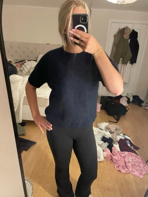 Mörkblå stickad tröja Gina Tricot - Mysig mörkblå stickad tröja från Gina Tricot med korta ärmar och rund halsringning. Tröjan har en enkel och stilren design, perfekt att matcha med både jeans och kjol. Materialet är fluffigt och ger en skön känsla.
