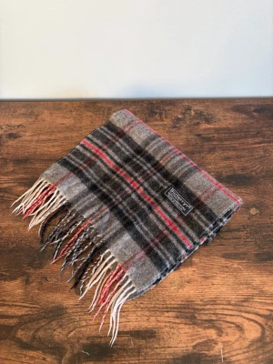 Burberry Halsduk - Vintage Burberrys halsduk i 100% lambswool. Made in England. Klassisk check i mörkare/bruna toner med diskret och tidlös look. Väldigt bra skick med endast mindre tecken på användning. Perfekt för en clean casual/old money stil.
