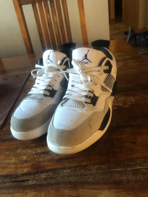 Air Jordan 4 Retro White/Black - Säljer ett par Air Jordan 4 Retro sneakers i vitt, svart och grått. Använda några gånger bara. Pris kan såklart sänkas.