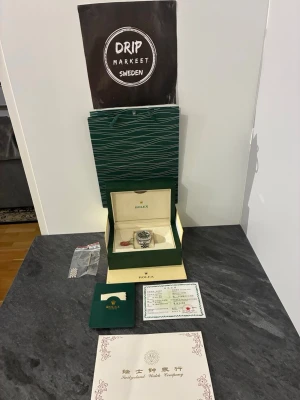 Herklocka  - Säljer en stilren herrklocka i silver med klassisk länkarmband och svart urtavla. Klockan kommer med originalbox, certifikat och extra länkar. Perfekt för dig som vill ha en ikonisk accessoar från ett av världens mest kända klockmärken.