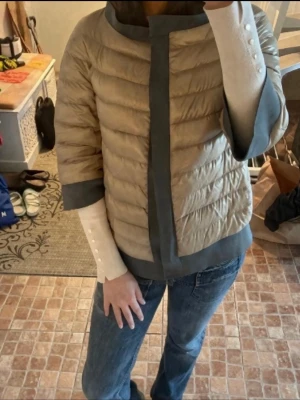 Beige dunjacka från Herno - Snygg beige dunjacka från Herno med glansigt material och kontrasterande gråblå detaljer längs kanterna. Perfekt om du gillar Stockholmstil. ‼️ JAG ÄR VILLIG ATT DISKUTERA PRISET VID SNABB AFFÄR‼️