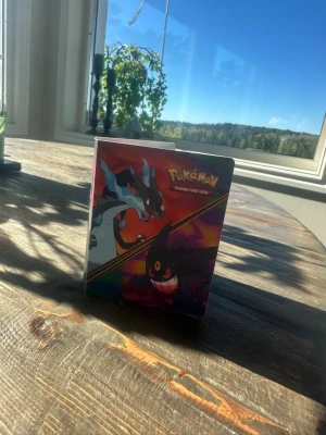 Pokémon samlarkortspärm - Pokémon samlarkortspärm med färgglatt omslag som visar Mega Charizard och Mega Gengar. Pärmen är gjord av plast och innehåller flera sidor för att förvara och visa upp Pokémonkort. Perfekt för dig som vill organisera din samling. Det kommer pokemonkort med som är värda mer än 200kr och några vid 20kr delen och dom kommer med. Korten är japanska och engelska. Och ni betalar 50kr för leverans  det är väldigt bra kort!