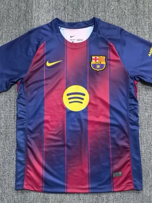 FC Barcelona matchtröja Nike - Säljer en officiell FC Barcelona matchtröja från Nike med klassiska blå och vinröda ränder. Tröjan har klubbmärke på bröstet, gul Nike-logga och Spotify-logga i mitten. Tillverkad i lätt och ventilerande polyester, perfekt för fotbollsträning eller support.