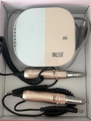 Elektrisk nagelfil Nailster - Säljer en elektrisk nagelfil från Nailster med touchdisplay och ergonomisk design. Filen är beige och silver, har en slimmad form och klarar upp till 35 000 RPM. Perfekt för att forma och polera naglar med precision. Använd ett par gånger endast, följer med både det använda ”handstycket” samt ett helt nytt. Även det använda fungerar såklart. Stödet följer också med, men syns inte i bild. Nypris 1299 kr.