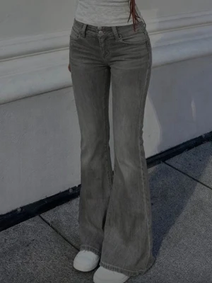 Grå bootcut jeans mid waist - Grå bootcut jeans med  klassiska fem fickor. Jeansen har utsvängda ben och två knappar, en lätt tvättad look. Perfekta för en trendig och avslappnad stil.