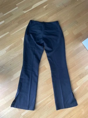 Svarta kostymbyxor från BikBok - Snygga svarta kostymbyxor från BikBok med klassisk rak passform och pressveck. Byxorna har två bakfickor och stängs med dragkedja och knapp. Perfekta för en stilren look och enkla att matcha med olika toppar. De är nya utan prislapp och har aldrig kommit till användning. Ordinarie pris 500 kr
